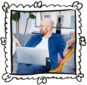En bild på Anton sittandes i en soffa med en dator i sitt knä, han håller upp armarna och har ett rycker-på-axlarna-uttryck.